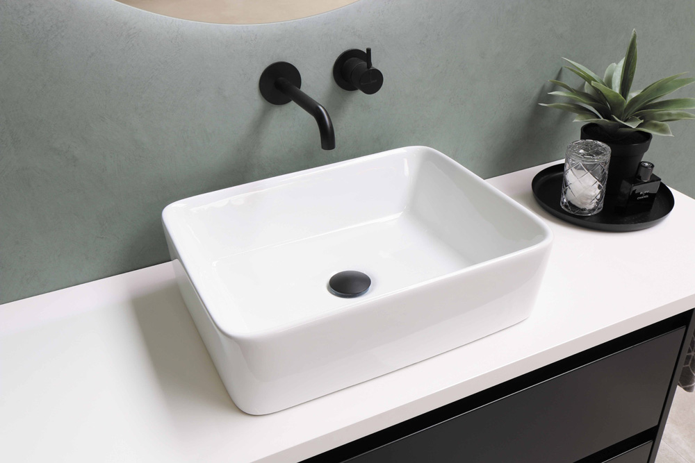 a white basin sink on top of a white counter with a black faucet coming out of the wall